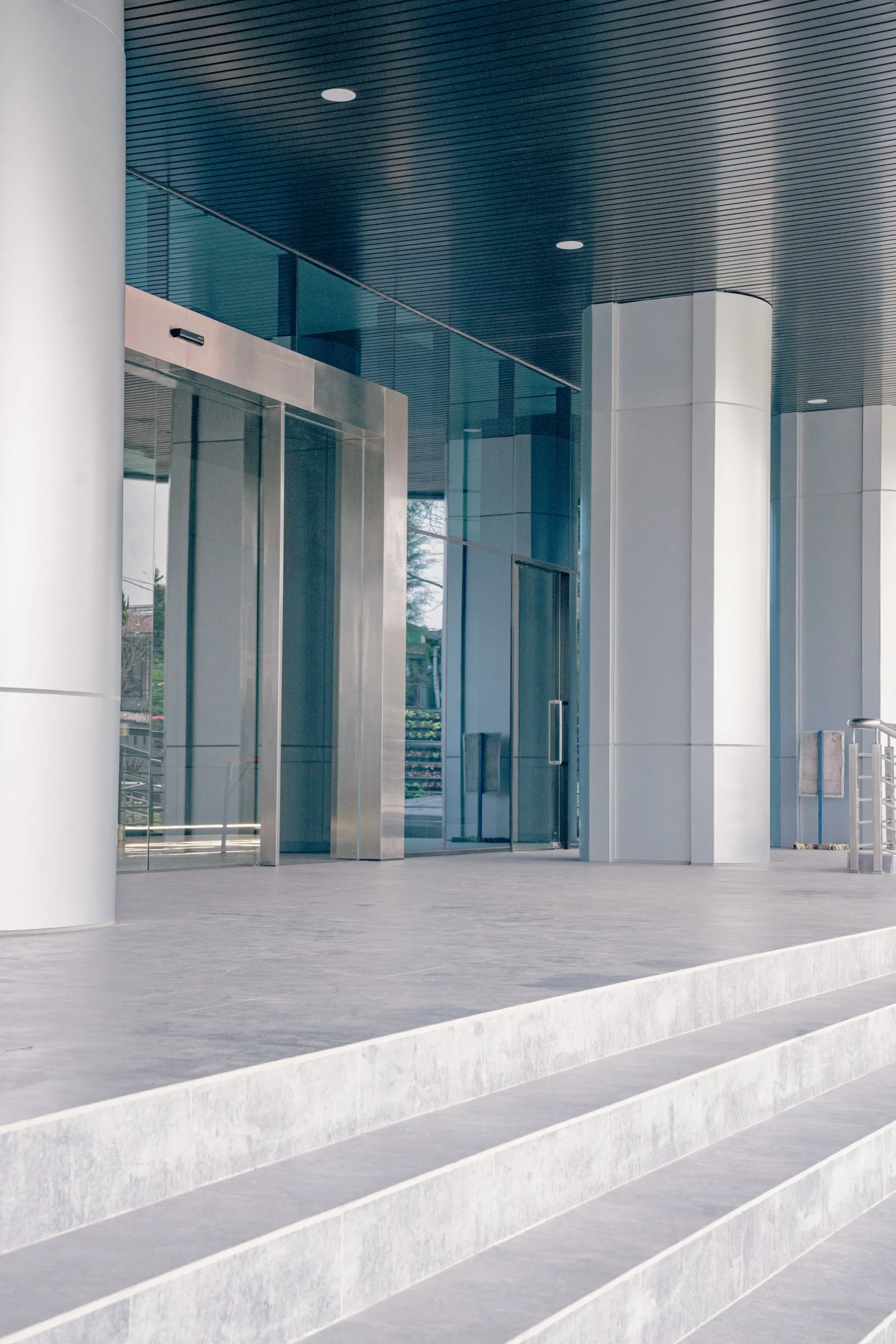 Entrée vitrée d’un bâtiment professionnel, avec porte automatique et éclairage encastré