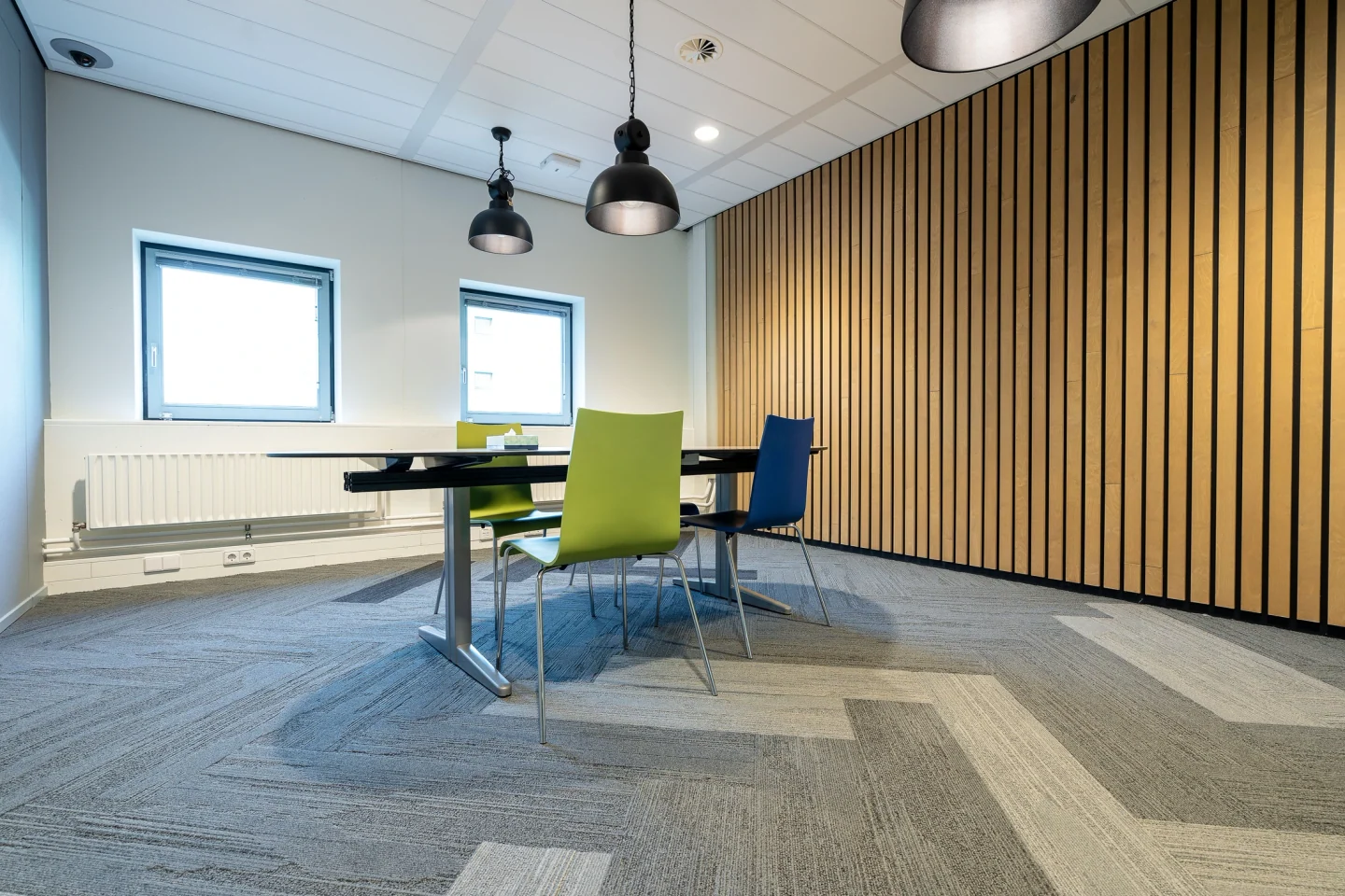 Salle de travail avec prises intégrées à une goulotte murale et table de réunion